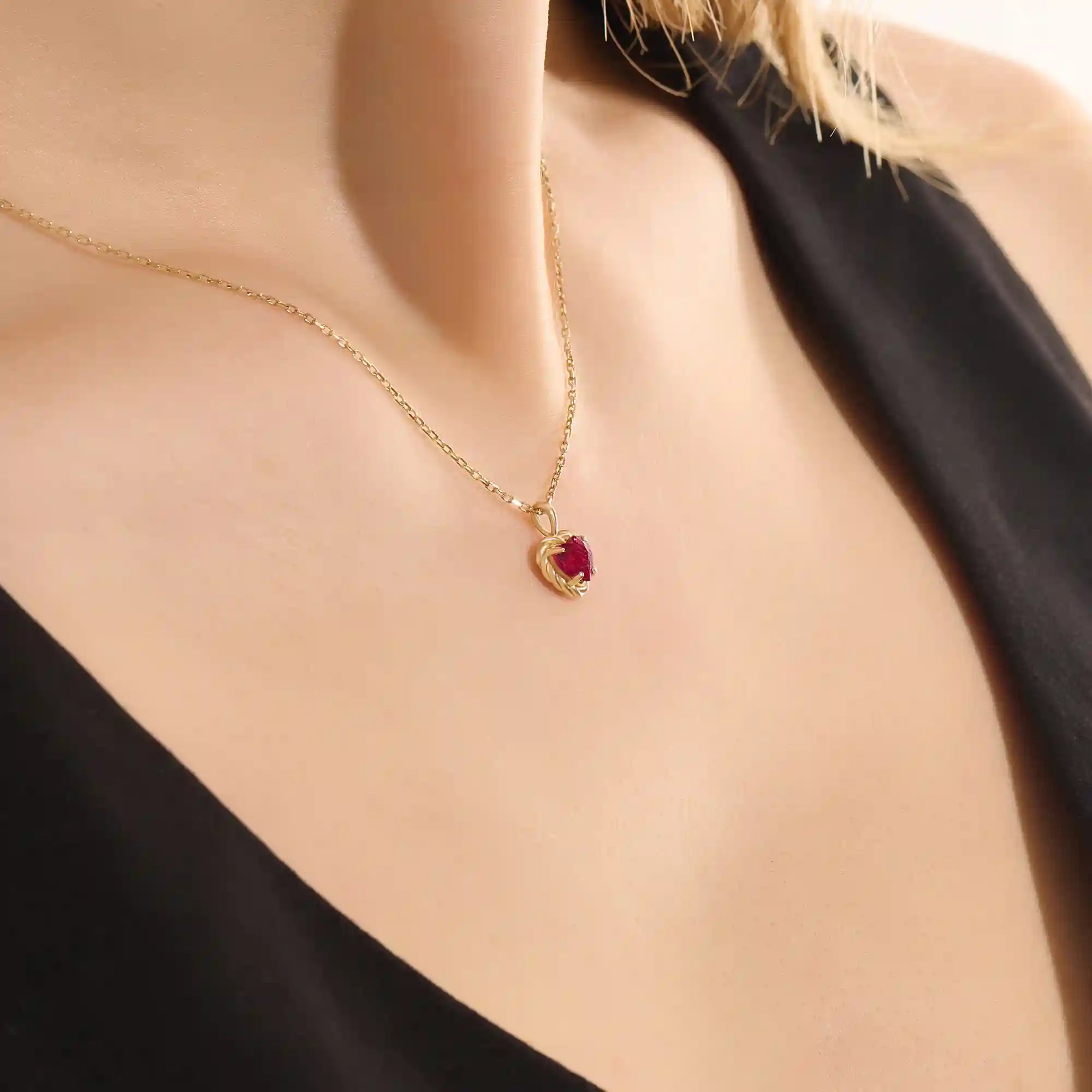 Woman wearing a 14k solid gold heart necklace with a vibrant lab-created ruby. Romantic and timeless gemstone pendant. Perfect for layering or wearing solo.