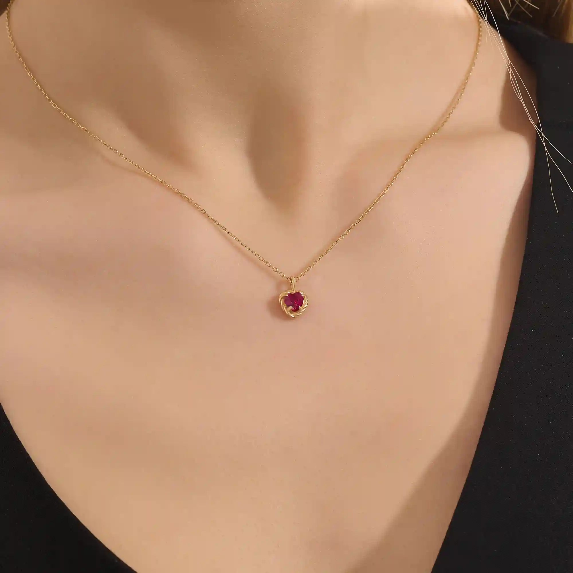 Woman wearing a 14k solid gold heart necklace with a vibrant lab-created ruby. Romantic and timeless gemstone pendant. Perfect for layering or wearing solo.