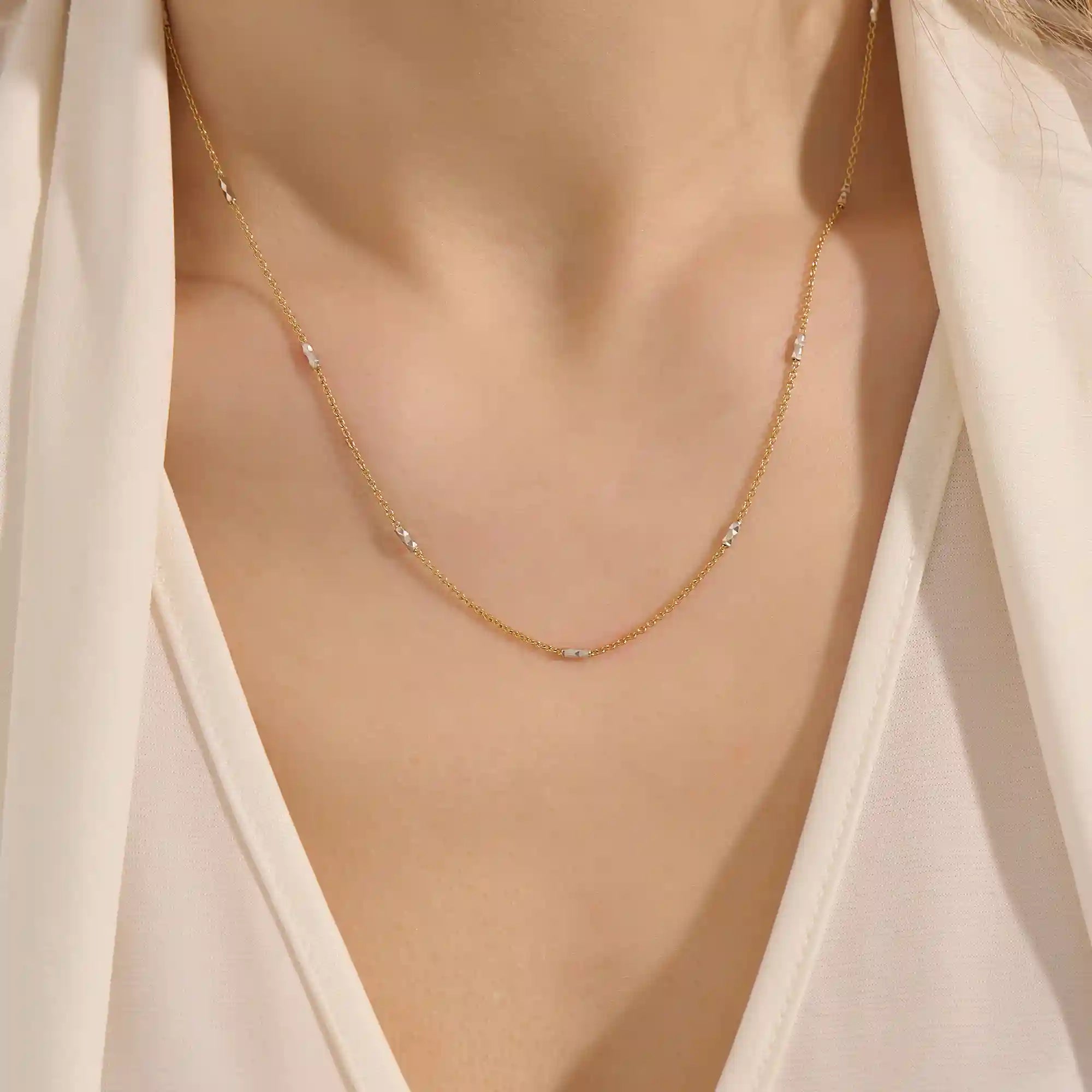 Woman wearing a 14k solid gold mixed metal bar chain necklace with polished yellow and white gold segments. A unique, eye-catching design for daily looks. Great for bold layering or worn alone.