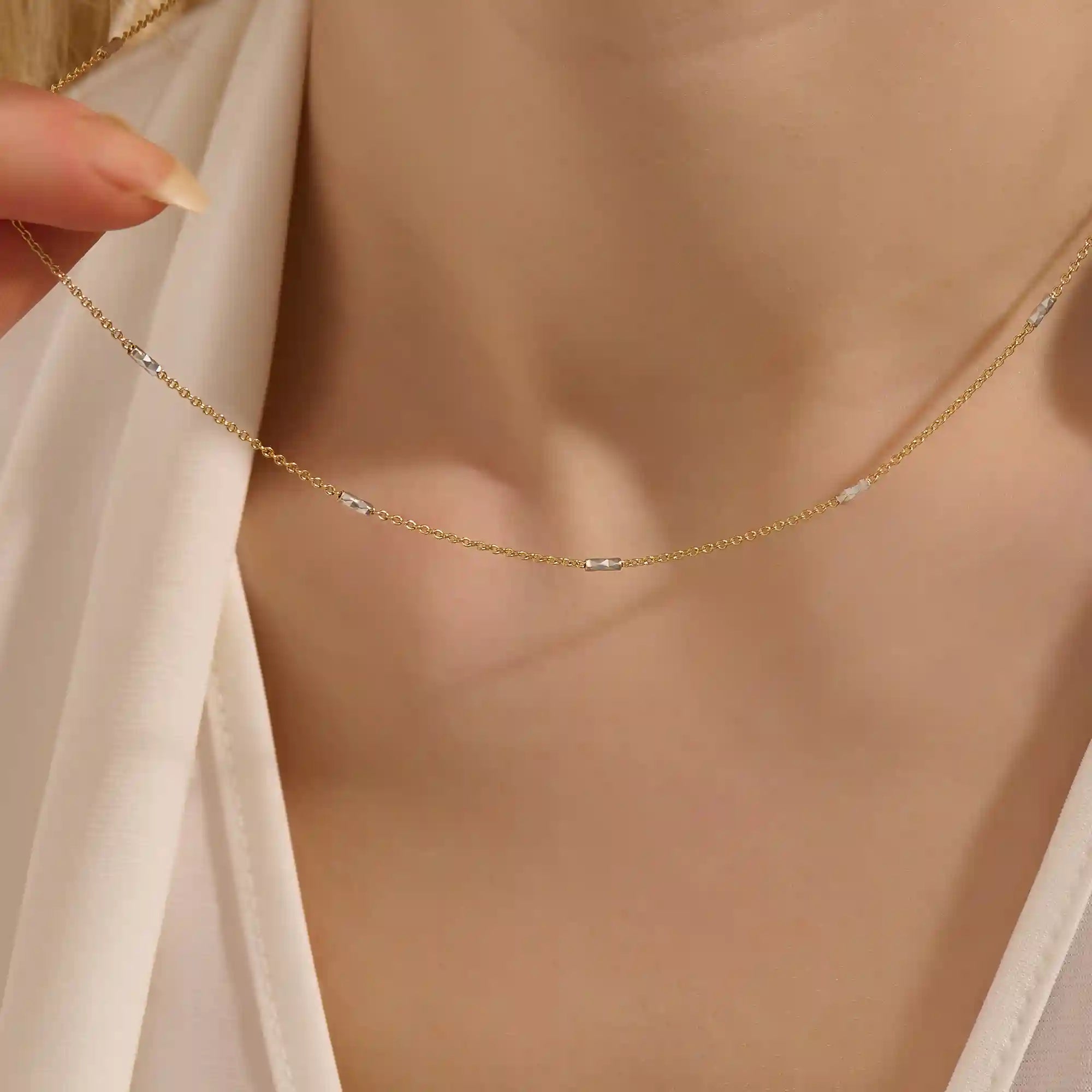 Woman wearing a 14k solid gold mixed metal bar chain necklace with polished yellow and white gold segments. A unique, eye-catching design for daily looks. Great for bold layering or worn alone.
