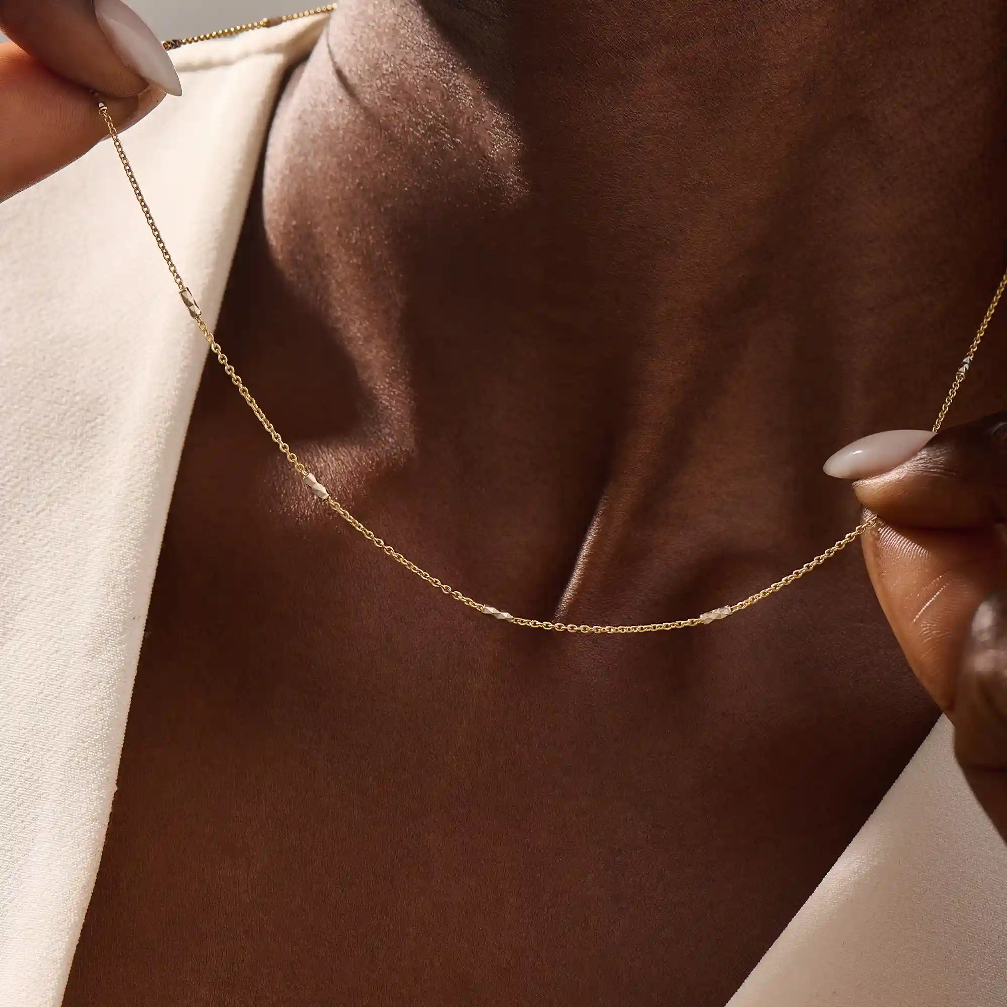 Woman wearing a 14k solid gold mixed metal bar chain necklace with polished yellow and white gold segments. A unique, eye-catching design for daily looks. Great for bold layering or worn alone.