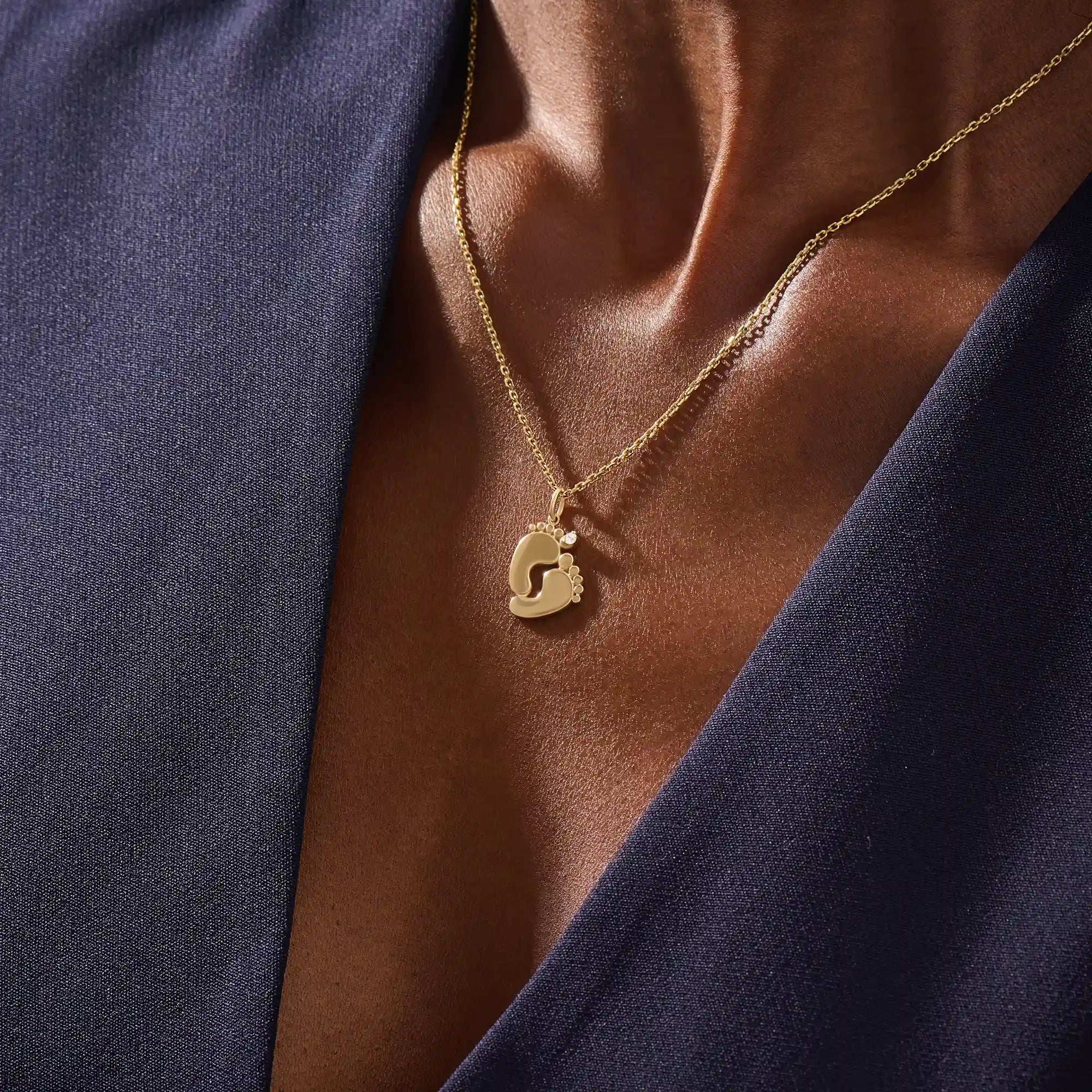 Woman wearing a 14k solid gold necklace with a baby foot pendant and sparkling moissanite detail. A meaningful and dainty gold piece celebrating motherhood and love. Ideal for layering or as a daily keepsake.