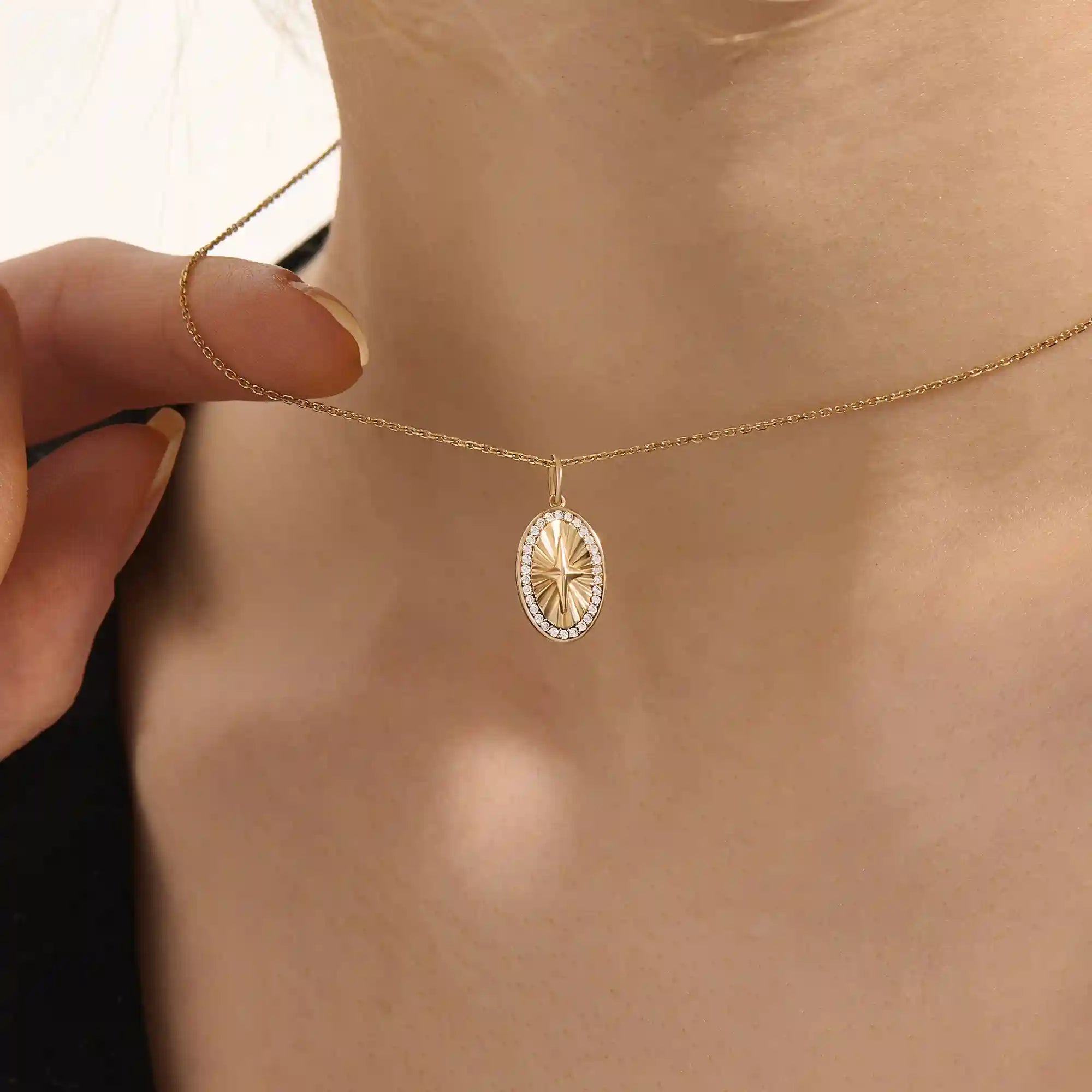 Woman wearing a 14k solid gold oval compass necklace featuring pave moissanite accents and a central 4-point star. Minimalist and meaningful pendant necklace. Ideal for layering or gifting.