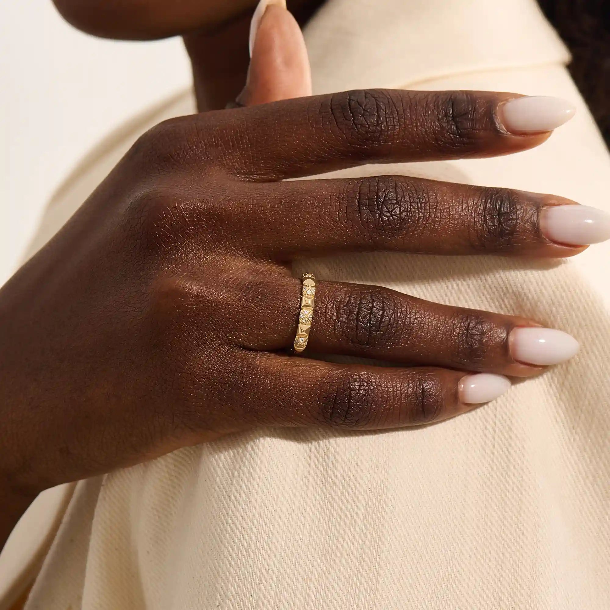 Woman wearing a 14k solid gold pyramid-style band with shimmering pave moissanites. A unique and structured gold ring. Ideal for weddings or everyday elegance.