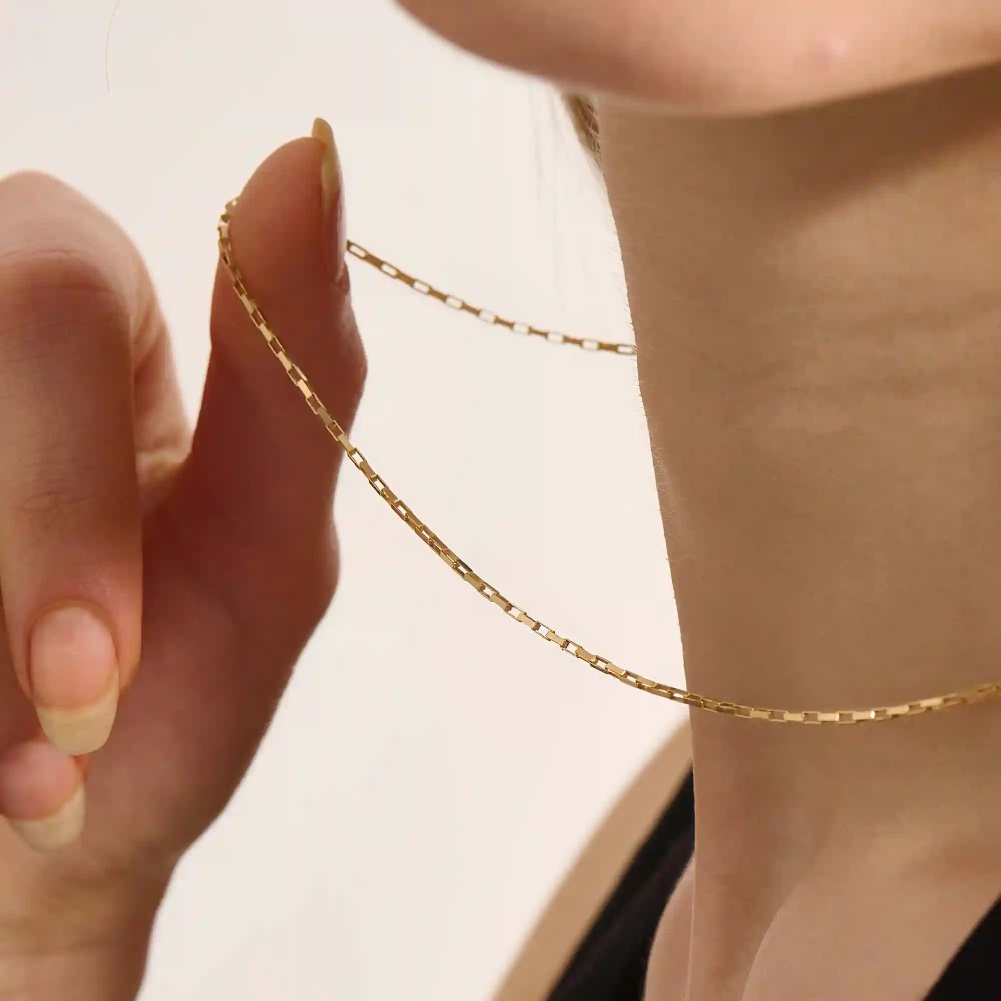 Woman wearing a 14k solid gold rectangle link chain necklace. Sleek and modern gold chain that adds a statement to any outfit. Easy to layer or wear solo.