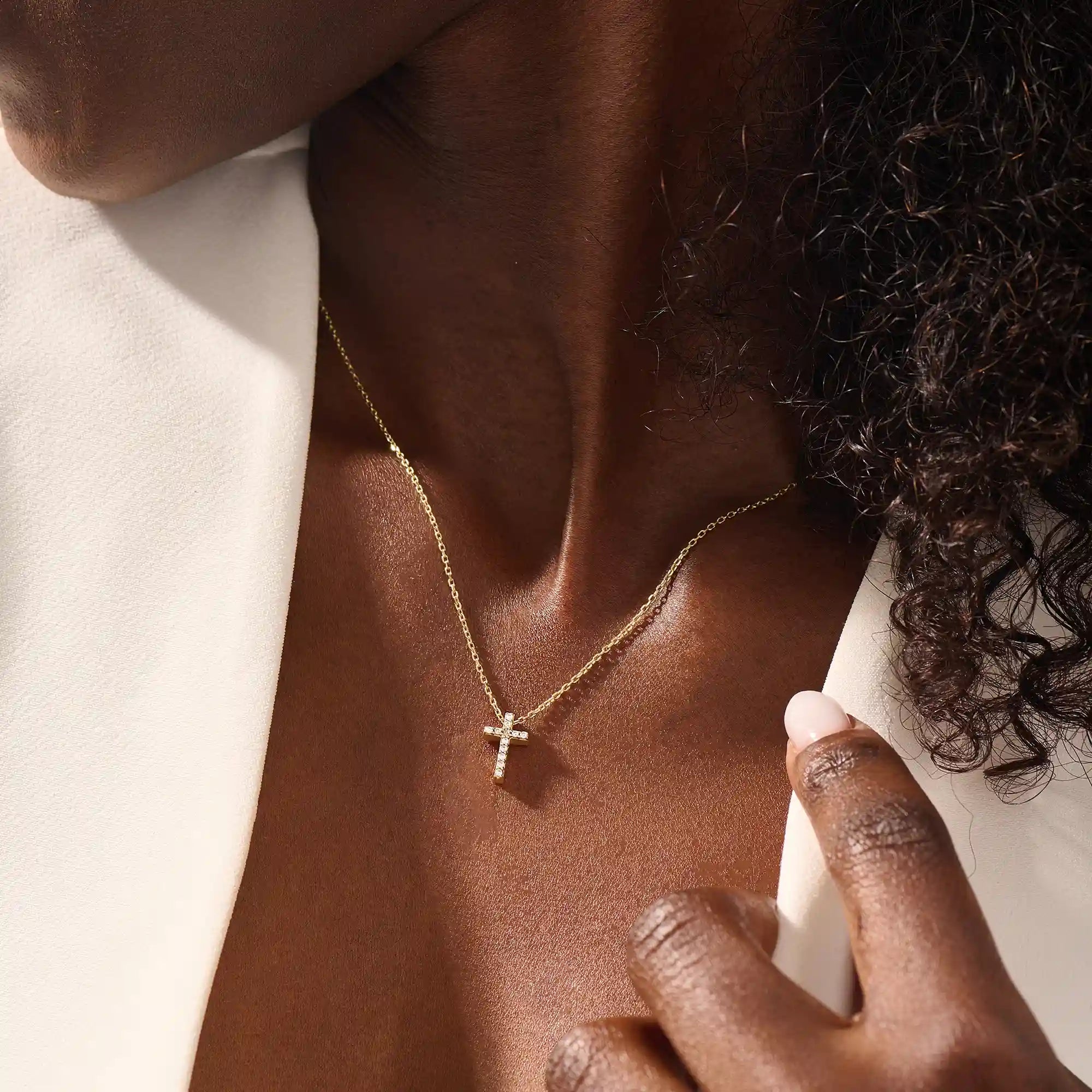 Woman wearing a 14k solid gold reversible cross necklace with pave moissanites on both sides. Subtle and elegant everyday jewelry. Designed for modern layering looks.