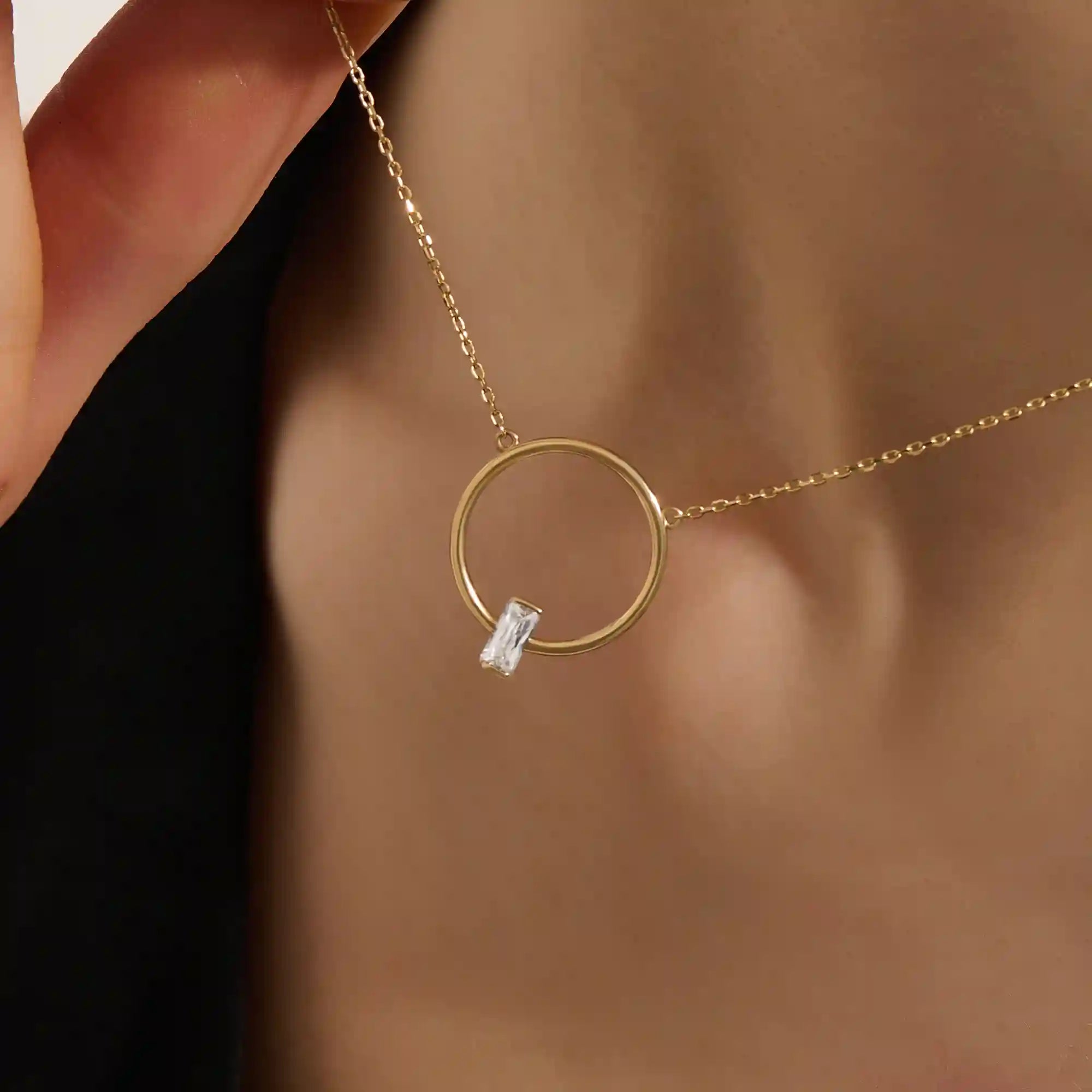 Woman wearing a 14k solid gold round karma necklace featuring a baguette moissanite in the center. Bold yet dainty gold design. Perfect for meaningful daily layering.