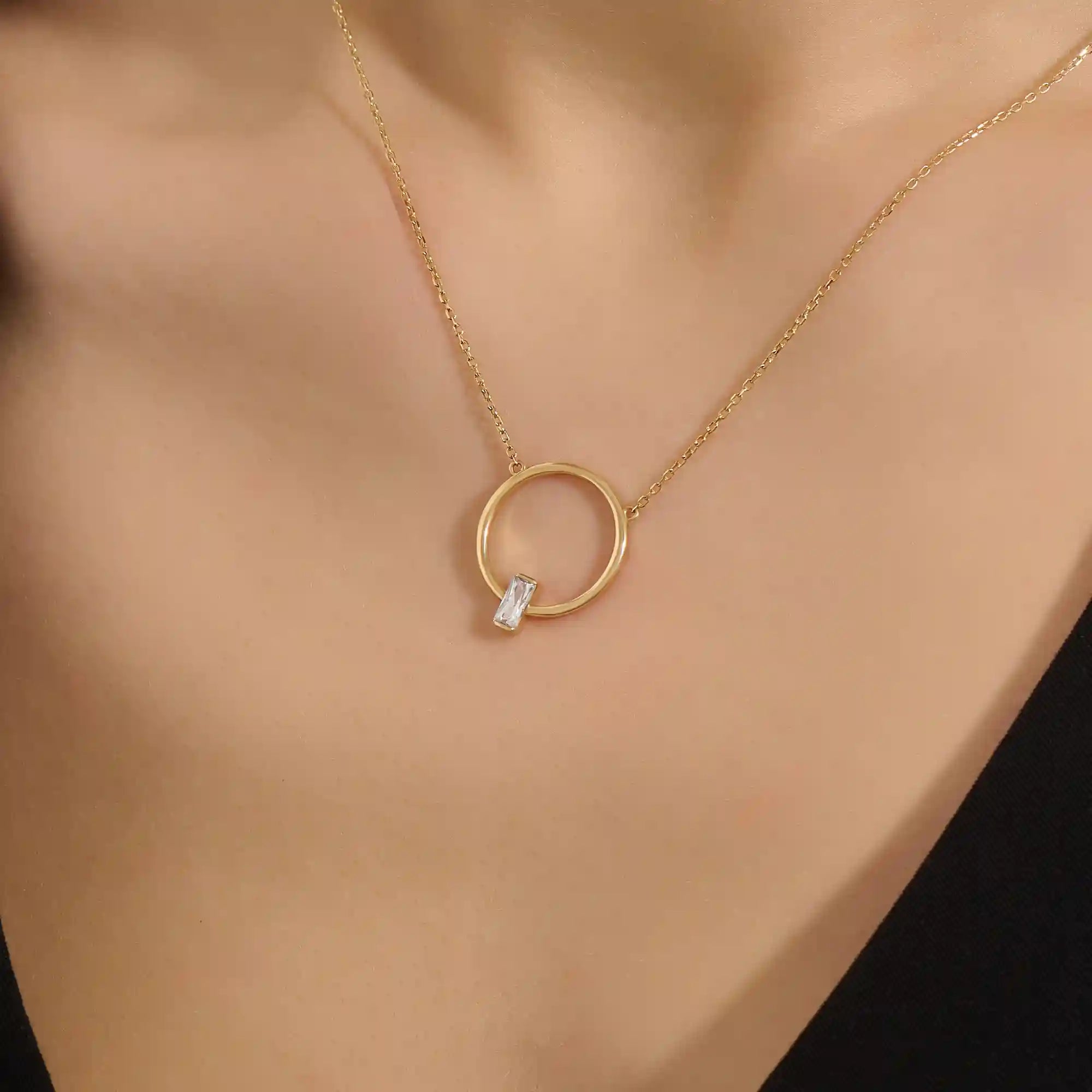 Woman wearing a 14k solid gold round karma necklace featuring a baguette moissanite in the center. Bold yet dainty gold design. Perfect for meaningful daily layering.