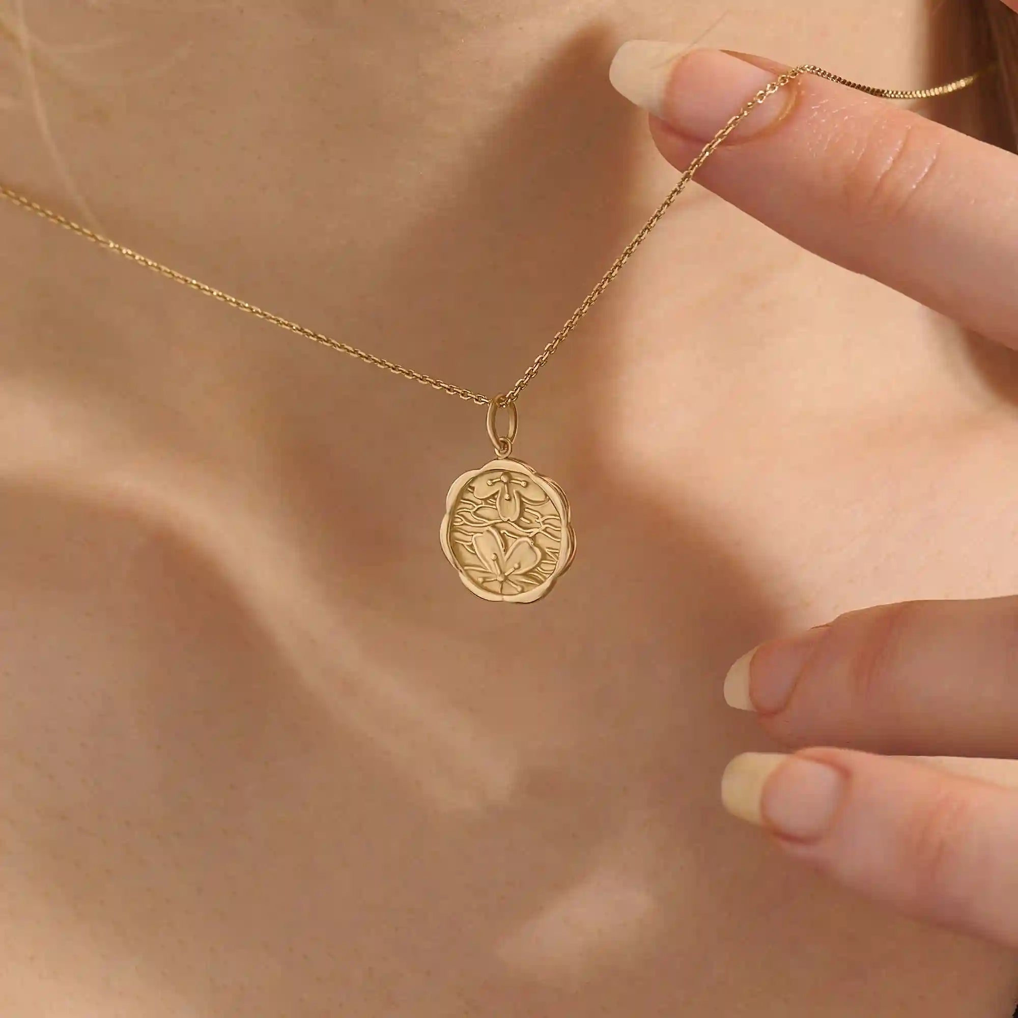 Woman wearing a 14k solid gold round necklace with a Sakura flower motif. Elegant floral-inspired jewelry for women. Perfect for everyday gold layering.