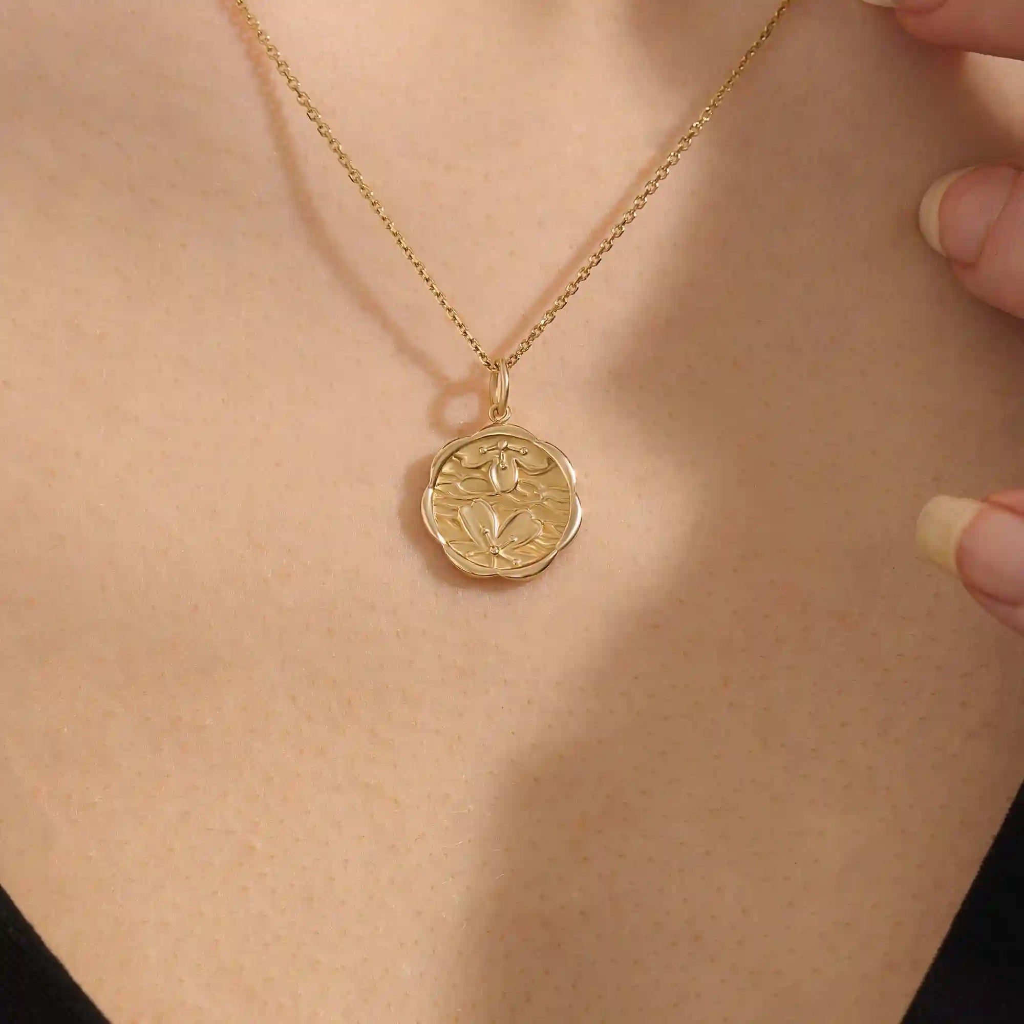 Woman wearing a 14k solid gold round necklace with a Sakura flower motif. Elegant floral-inspired jewelry for women. Perfect for everyday gold layering.
