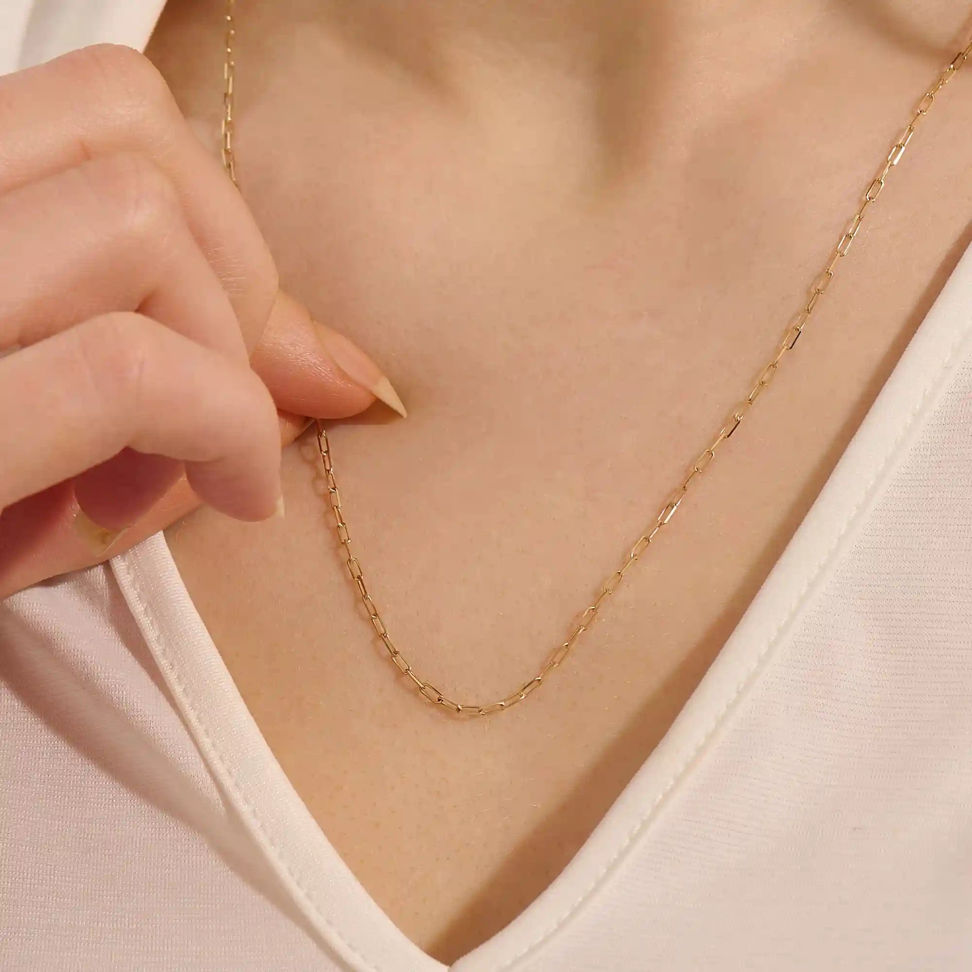 Woman wearing a 14k solid gold slim link chain necklace. Minimal and easy-to-style piece for everyday outfits. Perfect as a base for layering or simple looks.