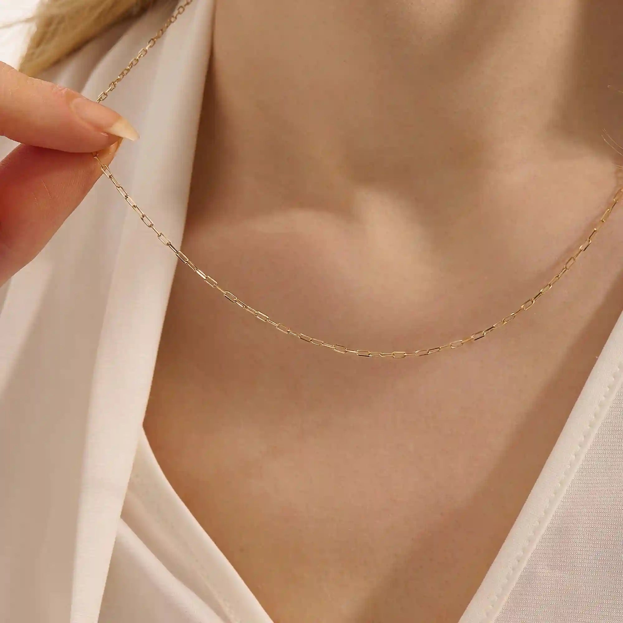 Woman wearing a 14k solid gold slim link chain necklace. Minimal and easy-to-style piece for everyday outfits. Perfect as a base for layering or simple looks.