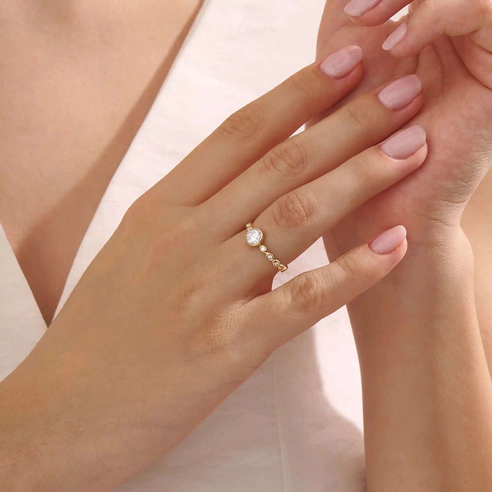 Woman wearing a 14k solid gold solitaire engagement ring with a bezel-set moissanite and fine band details. Elegant and minimal with a unique touch. Ideal for everyday wear and special moments.