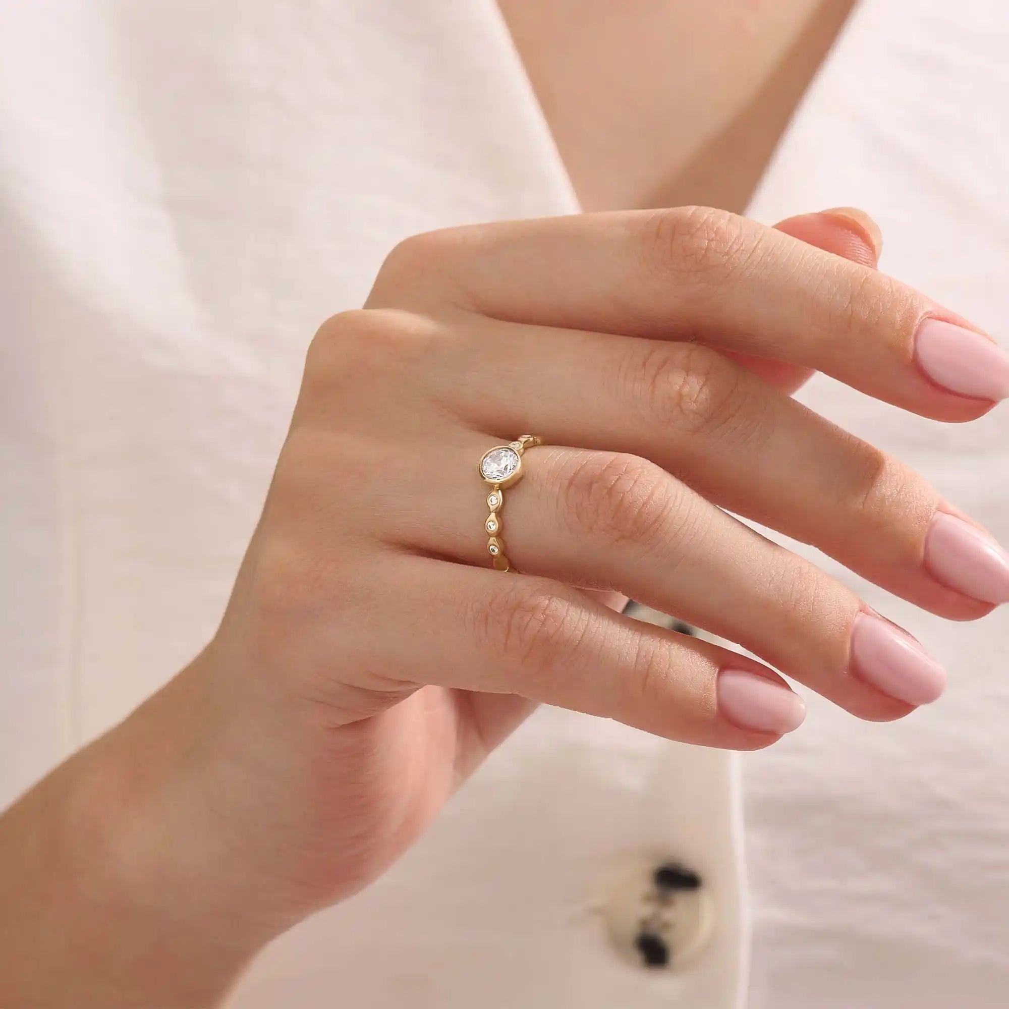 Woman wearing a 14k solid gold solitaire engagement ring with a bezel-set moissanite and fine band details. Elegant and minimal with a unique touch. Ideal for everyday wear and special moments.
