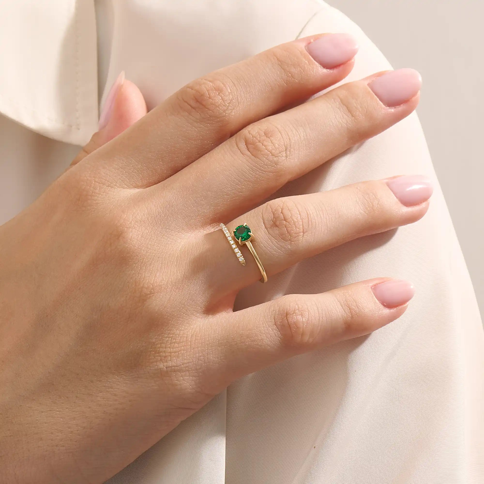 Woman wearing a 14k solid gold spiral ring with an emerald centerpiece. Eye-catching and modern with a touch of color. Ideal for everyday wear or special occasions.