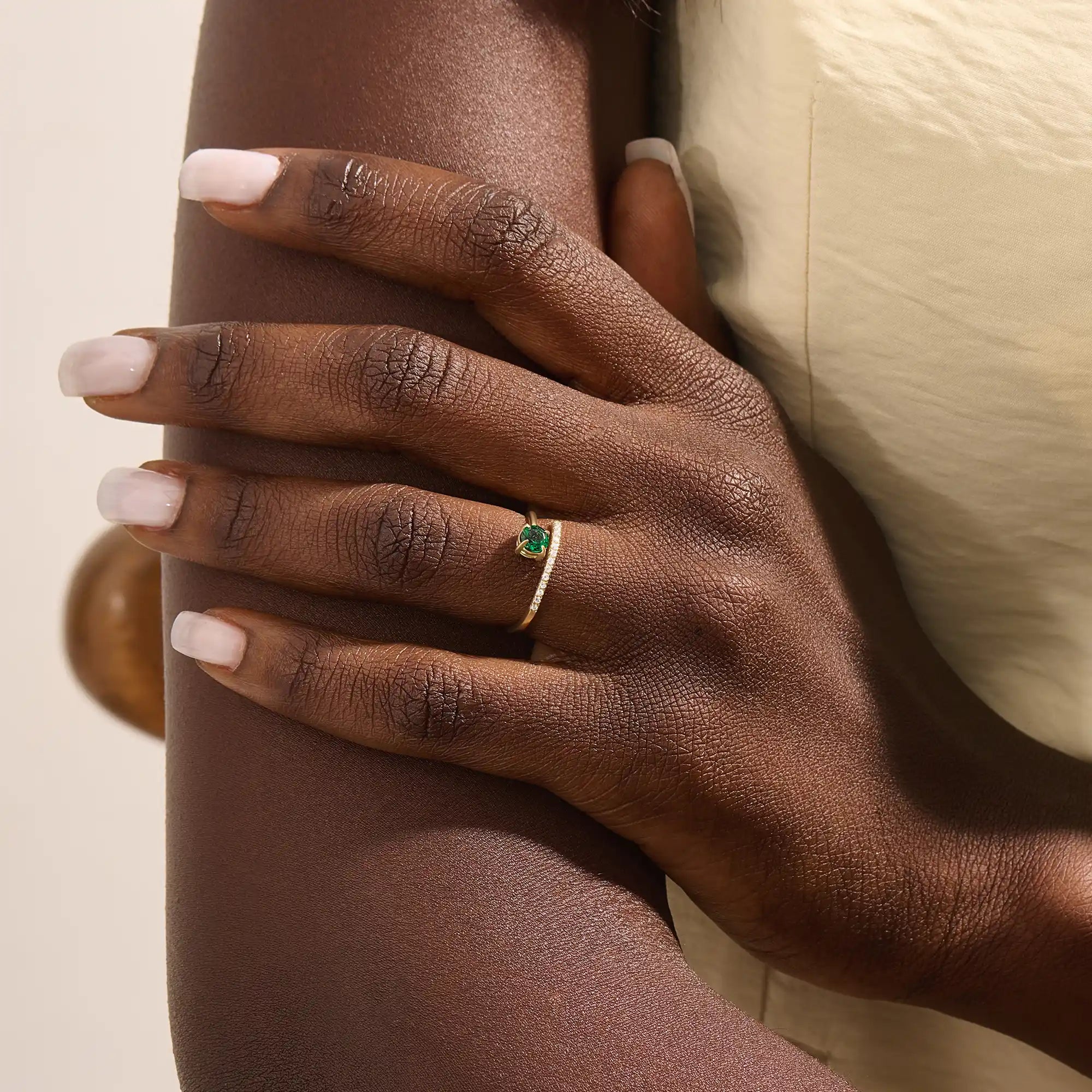 Woman wearing a 14k solid gold spiral ring with an emerald centerpiece. Eye-catching and modern with a touch of color. Ideal for everyday wear or special occasions.