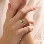 Woman wearing a 14k solid gold spiral ring with an emerald centerpiece. Eye-catching and modern with a touch of color. Ideal for everyday wear or special occasions.