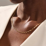 Woman wearing a 14k solid gold textured chain necklace with a soft shimmer. Stylish and easy-to-wear gold chain for daily looks. Perfect on its own or layered.
