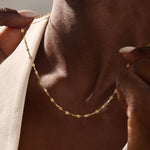 Woman wearing a 14k solid gold textured chain necklace with a soft shimmer. Stylish and easy-to-wear gold chain for daily looks. Perfect on its own or layered.