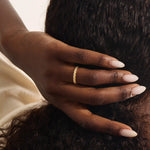 Woman wearing a 14k solid gold vine wedding band with flowing leaf-like engravings. A soft and romantic ring for daily styling. Perfect as a nature-themed or stacking band.