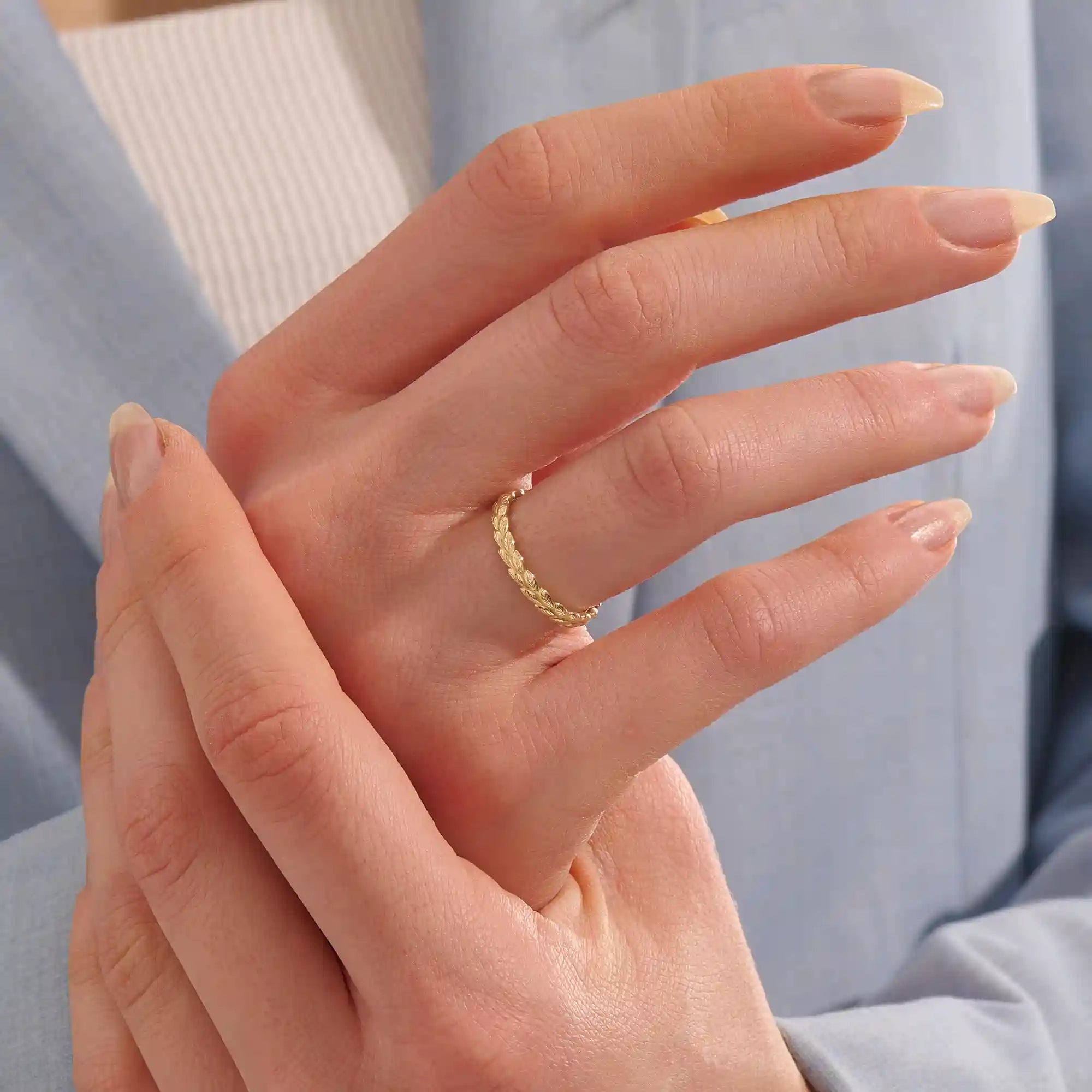 Woman wearing a 14k solid gold vine wedding band with flowing leaf-like engravings. A soft and romantic ring for daily styling. Perfect as a nature-themed or stacking band.