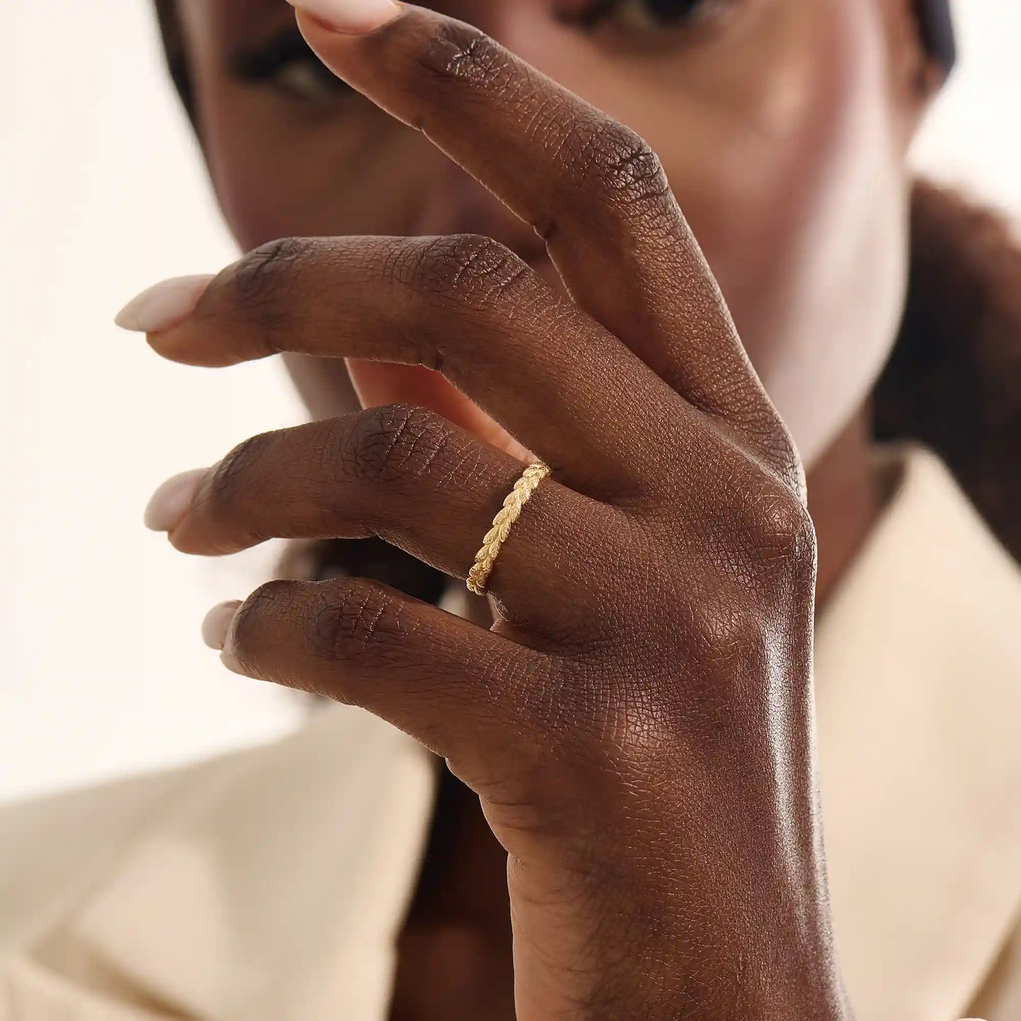 Woman wearing a 14k solid gold vine wedding band with flowing leaf-like engravings. A soft and romantic ring for daily styling. Perfect as a nature-themed or stacking band.