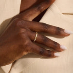 Woman wearing a 14k solid gold wedding band with delicate trio moissanite details. Elegant and meaningful design for daily styling. Great as a wedding or stacking ring.