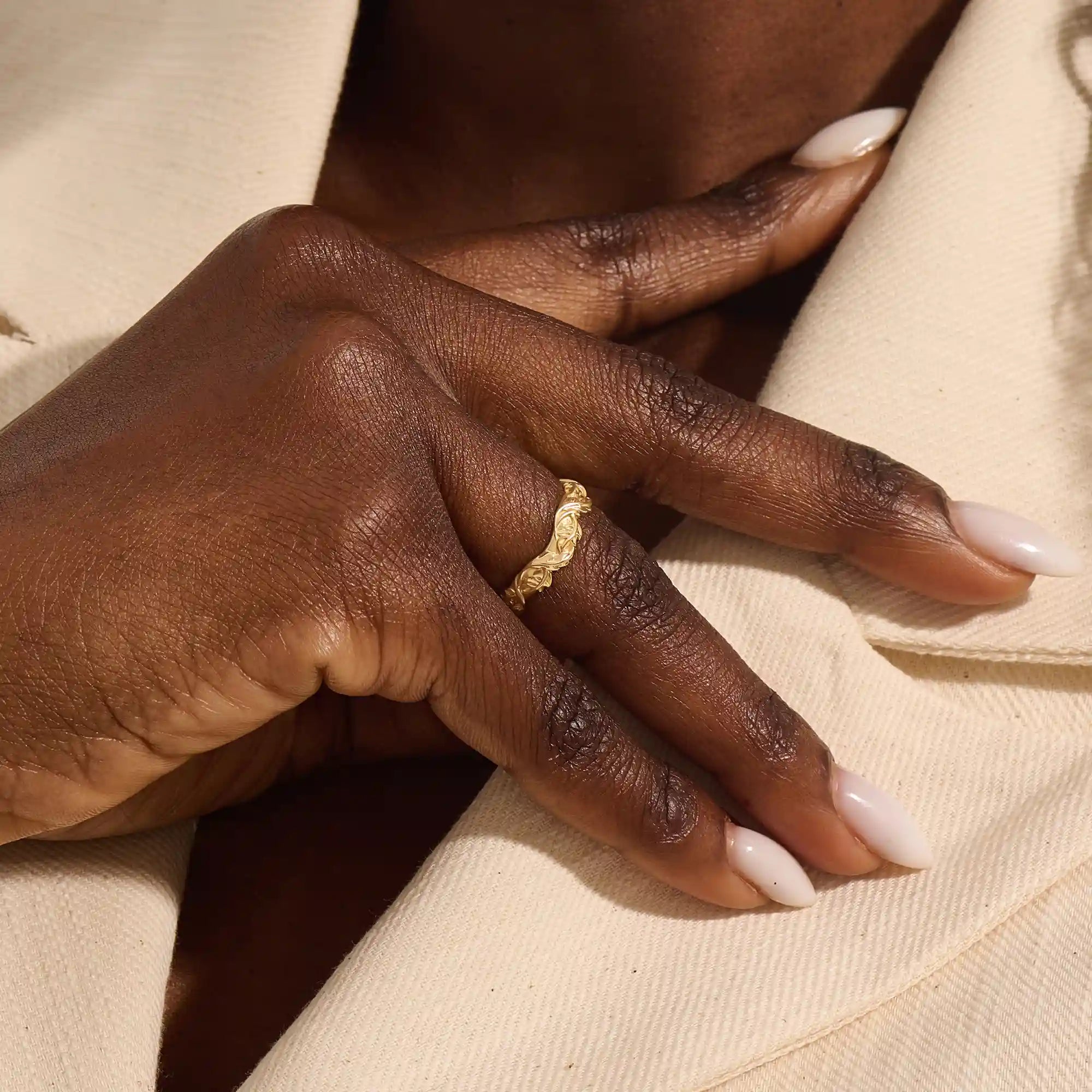 Close-up of a woman's hand wearing a 14k solid yellow gold ivy leaf wedding band. The detailed leaf motifs and smooth polished interior reflect a blend of natural inspiration and artisan craftsmanship, making it a distinctive and elegant choice for daily wear or special occasions.