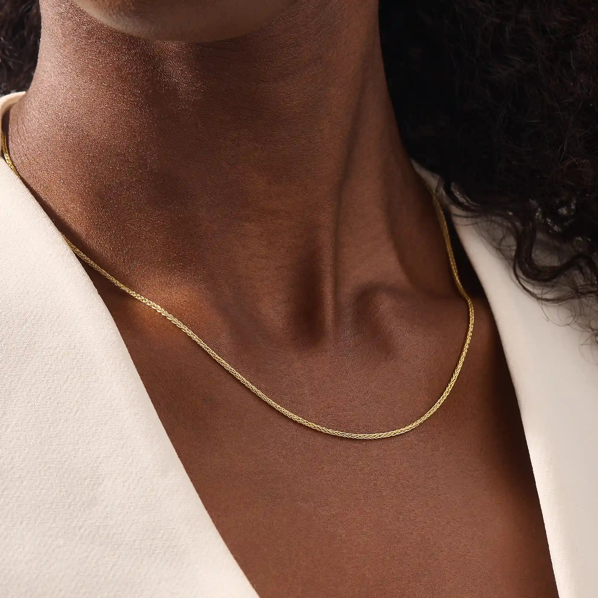 Woman wearing a 14k solid gold wheat chain necklace with a fine braided design. Subtle shine and elegant look for everyday outfits. Great as a standalone or layered piece.