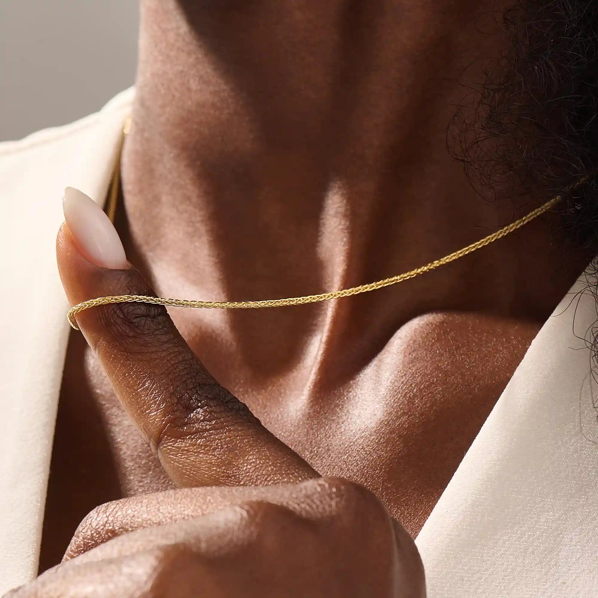 Woman wearing a 14k solid gold wheat chain necklace with a fine braided design. Subtle shine and elegant look for everyday outfits. Great as a standalone or layered piece.