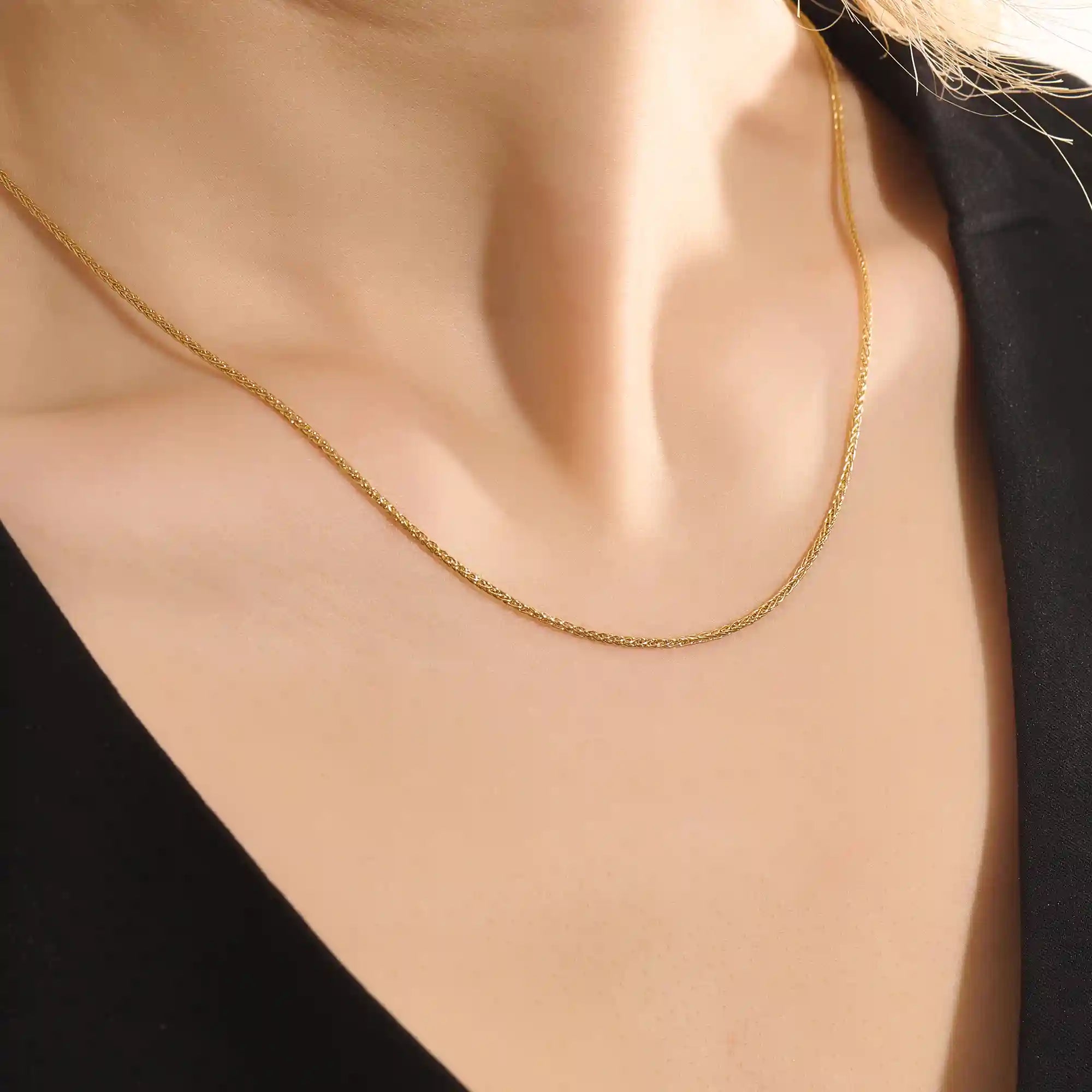 Woman wearing a 14k solid gold wheat chain necklace with a fine braided design. Subtle shine and elegant look for everyday outfits. Great as a standalone or layered piece.
