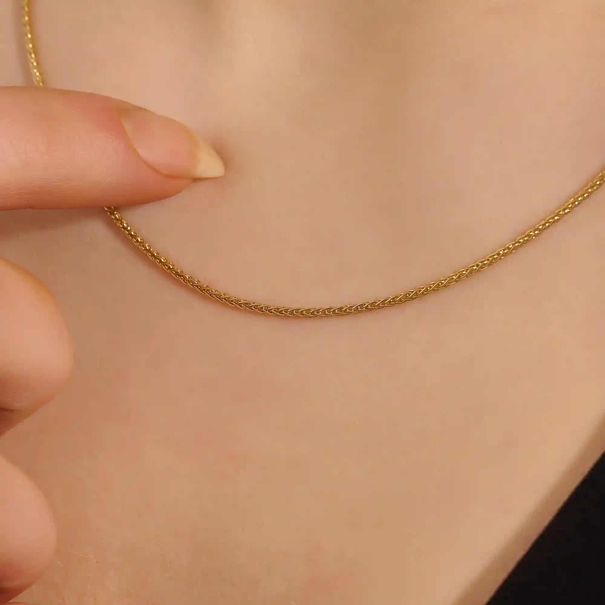 Woman wearing a 14k solid gold wheat chain necklace with a fine braided design. Subtle shine and elegant look for everyday outfits. Great as a standalone or layered piece.