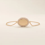 14k rose gold bracelet showcasing an oval charm encircled by pavé moissanite stones on a slim chain.

