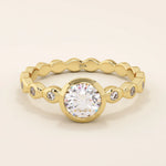 14k solid gold bezel-set solitaire engagement ring featuring a round moissanite and subtle detailing along the band. A modern twist on a classic style. Perfect for timeless proposals.
