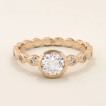 14k solid gold bezel-set solitaire engagement ring featuring a round moissanite and subtle detailing along the band. A modern twist on a classic style. Perfect for timeless proposals.