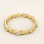 14k solid gold minimalist band ring with bezel-set moissanites around the band. Modern eternity statement jewelry for women.
