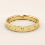 14k solid yellow gold wedding band adorned with tiny celestial star motifs, each featuring a delicate round moissanite at its center, evenly spaced around the polished band for a minimalist yet enchanting design.
