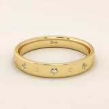 14k solid yellow gold wedding band adorned with tiny celestial star motifs, each featuring a delicate round moissanite at its center, evenly spaced around the polished band for a minimalist yet enchanting design.
