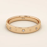 14k solid rose gold wedding band with petite starburst moissanite accents, evenly arranged across the smooth band to create a subtle celestial-inspired sparkle.
