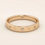 14k solid rose gold wedding band with petite starburst moissanite accents, evenly arranged across the smooth band to create a subtle celestial-inspired sparkle.
