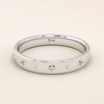 14k solid white gold wedding band featuring dainty celestial star engravings with shimmering moissanites set in their centers, offering a sleek and modern stacking ring style.
