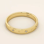 Side angle view of a 14k solid yellow gold wedding band showcasing raised star motifs with inset round moissanites, the highly polished edges enhancing its celestial charm.
