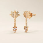 14k solid rose gold arrow-shaped stud earrings, showcasing delicate feathered ends and a pointed tip encrusted with white moissanite stones.
