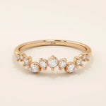 14k solid rose gold band adorned with a sequence of graduated moissanite stones in a delicate pavé setting.
