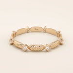 14k solid rose gold band adorned with alternating engraved leaf elements and shimmering moissanite stones.
