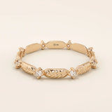 14k solid rose gold band adorned with alternating engraved leaf elements and shimmering moissanite stones.
