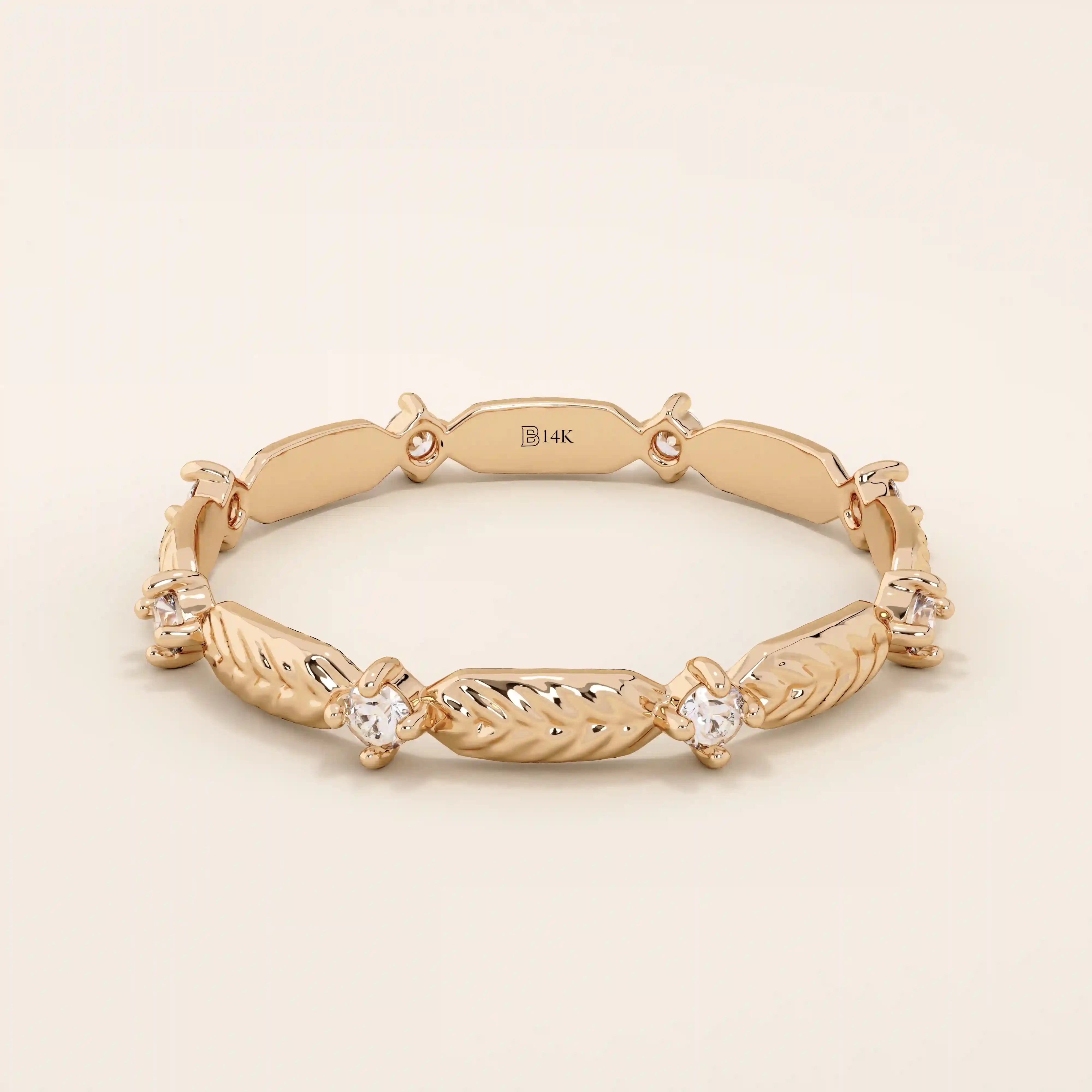 14k solid rose gold band adorned with alternating engraved leaf elements and shimmering moissanite stones.
