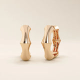 14k solid rose gold bone hoop earrings, blending a warm pink hue with sculpted, contemporary edges for a unique, modern aesthetic.
