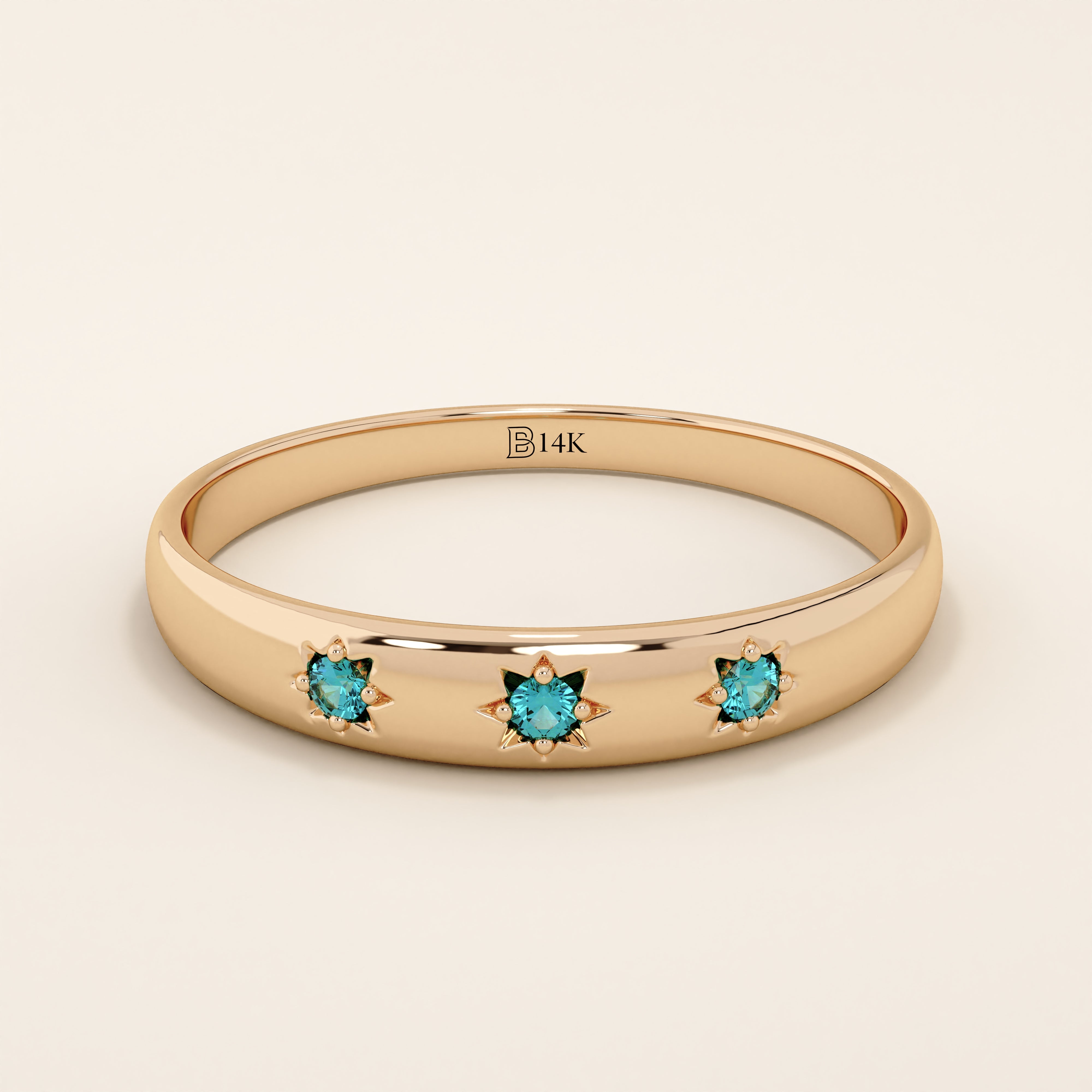 14k solid rose gold dome ring showcasing a trio of aquamarine gemstones accented with engraved star details.