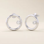 14k solid white gold open circle stud earrings featuring a floating bezel-set round moissanite accent.

